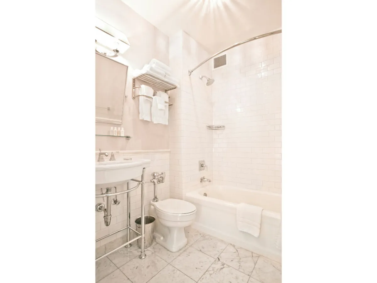 A serene en-suite bathroom featuring a deep soaking bathtub, elegant sink, plush towels, and a modern shower. The soft lighting and uncluttered design foster a calming, spa-like ambiance.